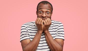 photo-anxious-young-black-man-bites-finger-nails-with-worried-expression_273609-44026